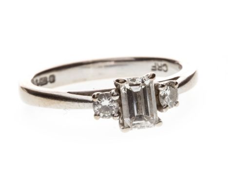 DIAMOND DRESS RING, set with an emerald cut diamond of approximately 0.36 carats flanked by two round brilliant cut diamonds 