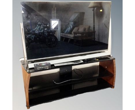 A Panasonic TX50DX802B LED TV on contemporary three tier stand, together with sound bar speaker, remotes and 3D glasses.