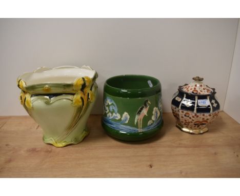 Two early 20th century Jardinieres, one having stork decoration and the other lillies sold with a ceramic jar with lid in the