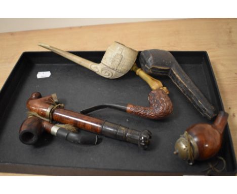 A collection of vintage and antique pipes, including large clay pipe with carved decoration, opium pipes and tobacco pipes.