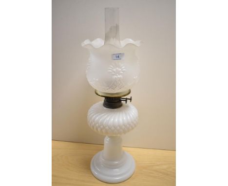 A Victorian milk glass oil lamp, with a moulded and embossed shade, measuring 55cm tall
