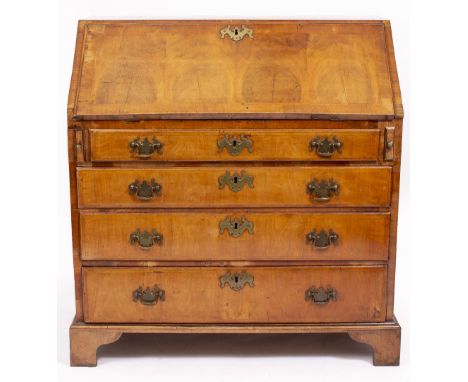 AN EARLY 18TH CENTURY WALNUT BUREAU the fall front enclosing a fitted interior with central well above four long drawers and 