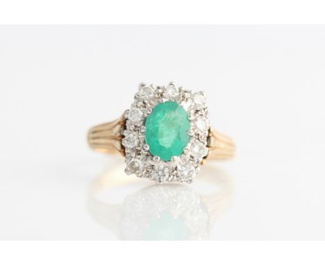 A 9ct yellow gold emerald and diamond cluster ring, set with a central oval cut emerald, measuring approx. 7x5mm, surrounded 