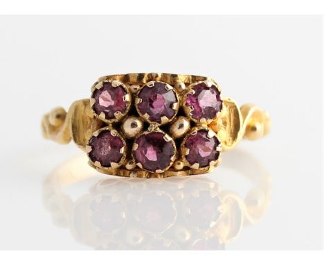 A Victorian 15ct yellow gold six stone garnet ring, set with six round cut garnets in two rows, each shoulder featuring scrol