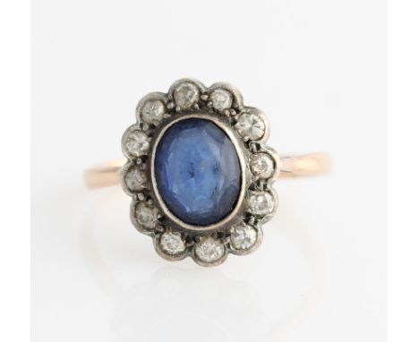 A blue paste and diamond cluster ring, set with a central oval cut blue paste surrounded by a border of twelve eight-cut diam
