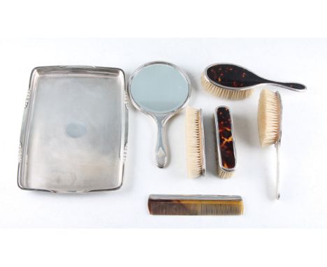 A matched silver and tortoiseshell dressing table set, comprising two hair brushes, two hand brushes, a comb and mirror, all 