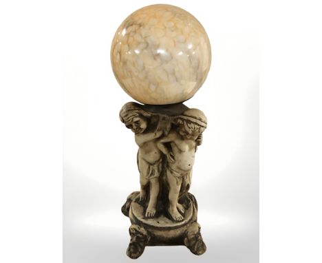 A figural pottery lamp base in the form of three cherubs, with mottled globular glass shade, height 52 cm. (requires rewiring