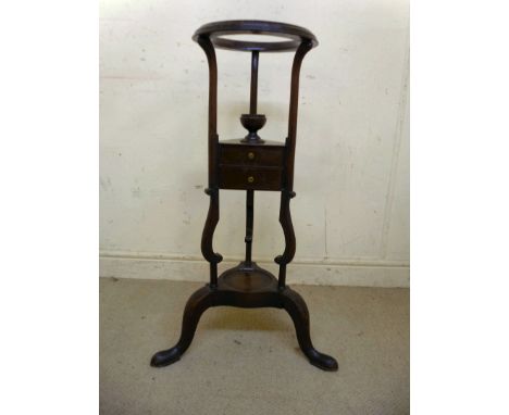 A George III mahogany washstand, having a moulded aperture, over a reservoir and two drawers and a dished base, raised on spl