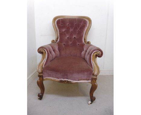 A late Victorian walnut showwood framed spoonback armchair, upholstered in part button brown fabric, raised on C-scroll carve