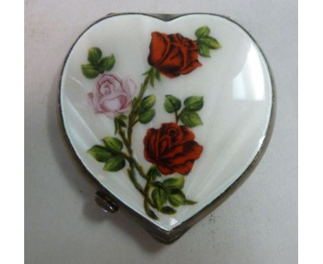 A mid 20thC silver powder compact of heart shaped design, the front panel decorated with red and white engine turned enamel d