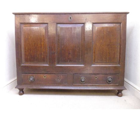 A George III oak chest, having a rising top, over a tri-panelled front and a pair of in-line drawers, raised on bulbous turne