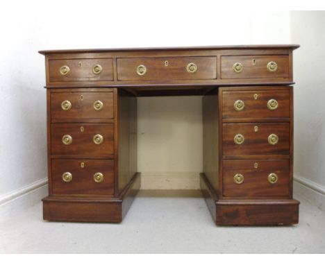 An early Victorian mahogany desk, having a brown faux hide scriber, over three inline drawers, raised on twin, three drawer p