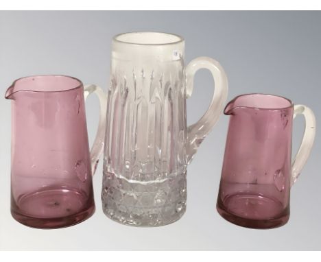 Two ruby glass jugs and a further clear jug, tallest 24 cm.