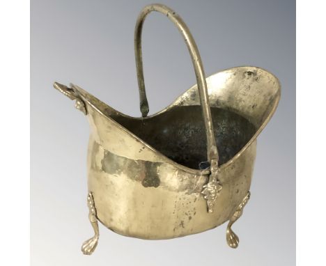A Victorian brass coal helmet on paw feet, length 48 cm.