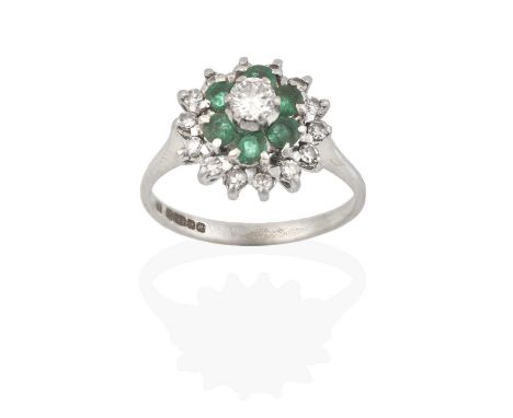 the raised round brilliant cut diamond within a border of round cut emeralds, to a further border of eight-cut diamonds, in c