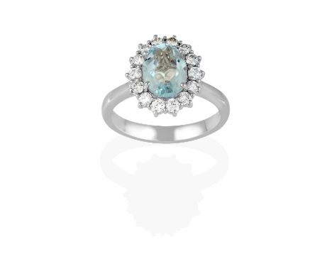 the oval cut aquamarine within a border of round brilliant cut diamonds, in claw settings, to a tapered shoulder plain polish