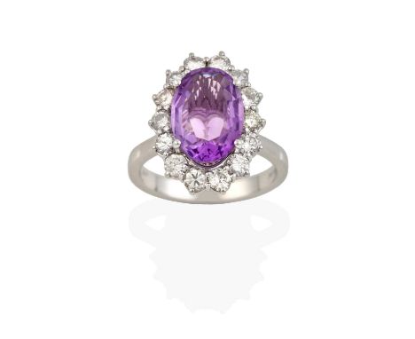 the oval cut amethyst within a border of round brilliant cut diamonds, in claw settings, to a tapered shoulder plain polished