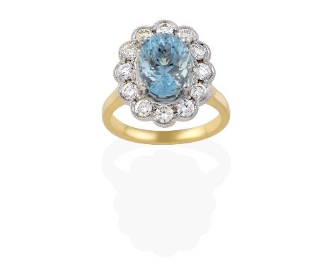 the oval cut aquamarine within a border of round brilliant cut diamonds, in white claw and millegrain settings, to a yellow t