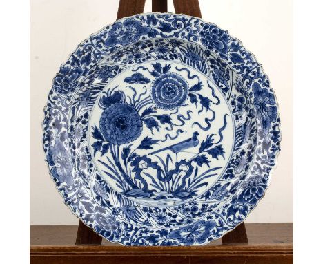 Blue and white porcelain chargerChinese, Kangxi period (1662-1722)having a moulded border with panels of peonies, foliate scr