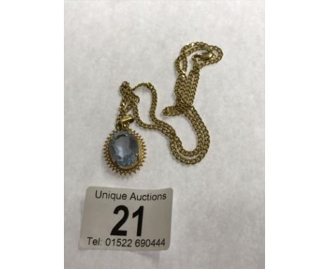 A 9ct gold chain (4 grams) with a yellow metal pendant set pale blue stone.