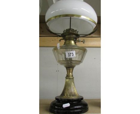 A brass oil lamp with clear glass font and complete with shade and chimney.