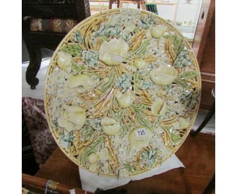 A fragile large ceramic plate which is heavily decorated with 3D roses and leaves by Zsolnay Pecs.  It has a firing crack in 