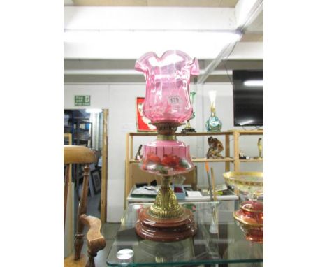 A Victorian oil lamp with cranberry glass shade.