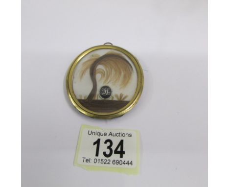A Georgian sweetheart pendant of finely worked hair with monogram on mother of pearl, glazed in an oval framed (NB: A sweethe