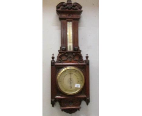 A carved oak barometer/thermometer.