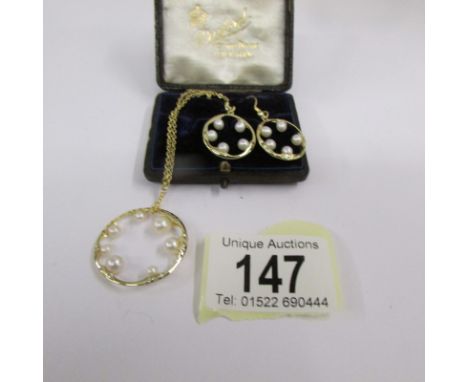 A cultured pearl pendant with matching ear pendants.