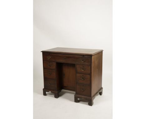 A MAHOGANY KNEEHOLE WRITING DESK, the rectangular top with a moulded border above a baize-lined brushing slide and long fitte