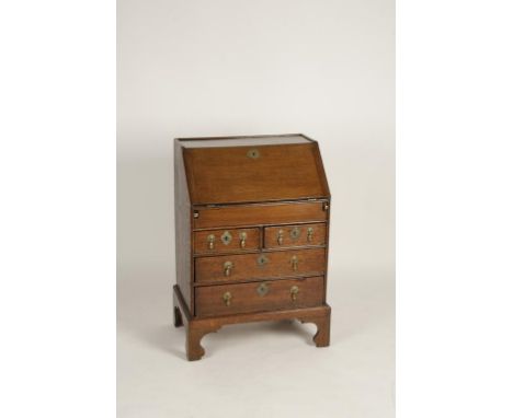 AN OAK "CHILDS" BUREAU, the sloping fall with moulded border enclosing a fitted interior with a central arch top cupboard fla