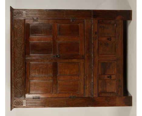 A LARGE OAK PRESS CUPBOARD with two four-panel doors within a carved and stop-fluted surround, above two short deep drawers, 