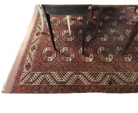 A BOKHARA TYPE SMALL CARPET worked with repeated octagonal motifs against a brick red ground, 152" x 93"