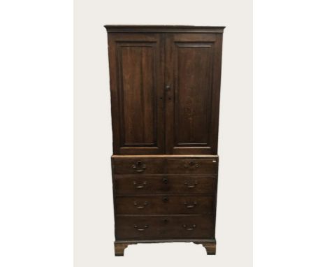 AN OAK PRESS OR HOUSEKEEPERS CUPBOARD, the top with two panelled doors enclosing a shelved interior, the lower section with t