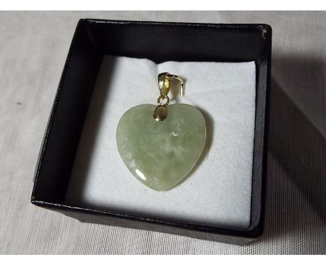 A lady's heart-shaped jade pendant with 14 carat gold mount 