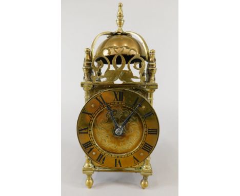 A brass lantern timepiece, with turned finials, shaped cresting on globular feet, the movement stamped France, 25cm high