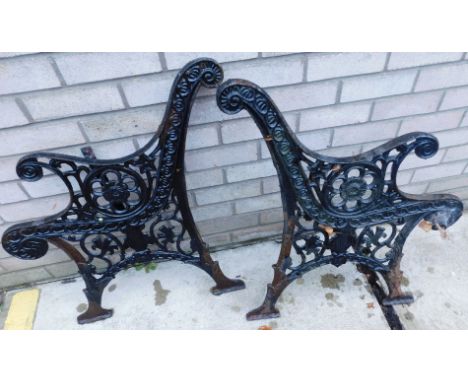 A pair of Victorian black painted cast iron garden bench ends, each decorated with leaves etc.