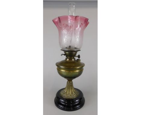 A Victorian brass oil lamp, with cranberry tinted etched shade, tapering base and ceramic plinth, 41cm high