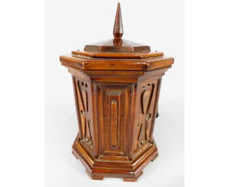 A mahogany tea caddy, the octagonal hinged lid with a tapering finial, enclosing a lined interior, the base with panelled sid