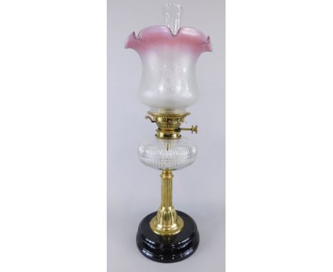 A Victorian oil lamp, with cut glass clear reservoir, brass and ebonised terracotta base, with later etched cranberry shade a