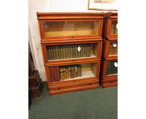Three-tier glazed sectional bookcase with single drawer to base in stained light wood, probably second or third quarter 20th 