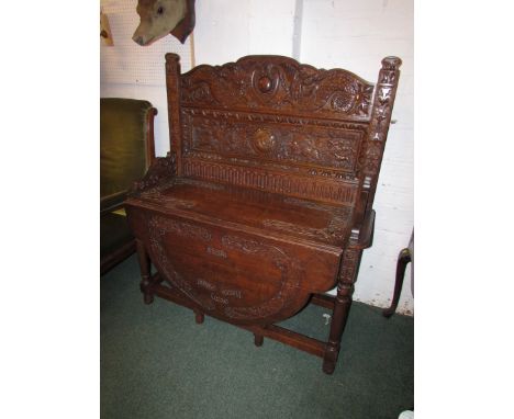 An 1880's oak heavily carved sideboard with lap semi-circular table front, carved with mythical serpents, boar and hounds, an