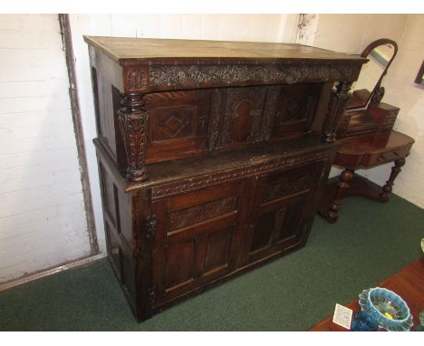 A late 17th century carved oak court cupboard, the top with two tapering columns and lozenge carved single door to each end, 