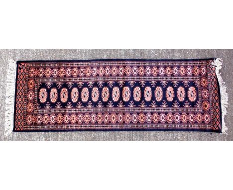 Eastern carpet runner, with central pale yellow lozenges on a dark blue ground, 61 x 172 cm 