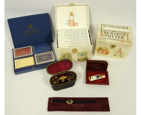 Two cased sets of Beatrix Potter books, cased opera glasses, and a BMJ lighter with enamel peacock case, playing cards, boxed