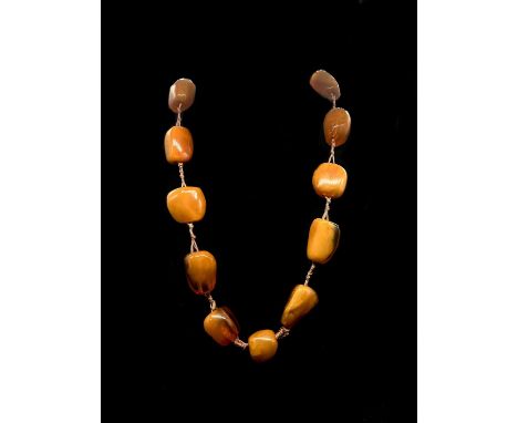 A large vintage hand tied egg yolk/butterscotch amber bead necklace, formed of fourteen irregular shaped beads, the largest b