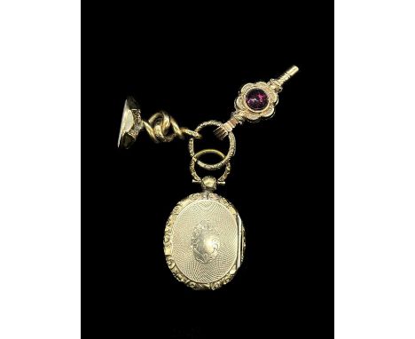 A Victorian yellow metal oval locket, centred with a section of plaited hair, a yellow metal pocket watch key and a yellow me