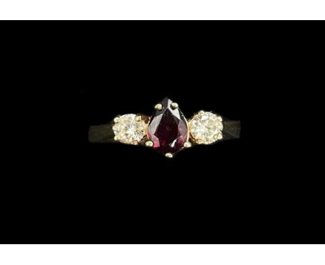 A 9ct yellow gold three stone ruby and diamond ring, the five claw set central pear shaped ruby flanked by twin round brillia