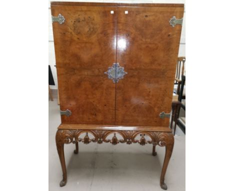 A Queen Anne style cocktail cabinet in crossbanded burr walnut, enclosed fitted interior with mirror and slide out shelf, orn